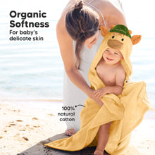 Load image into Gallery viewer, Child wrapped in a yellow hooded towel with a giraffe design, sitting on a beach with a woman.
