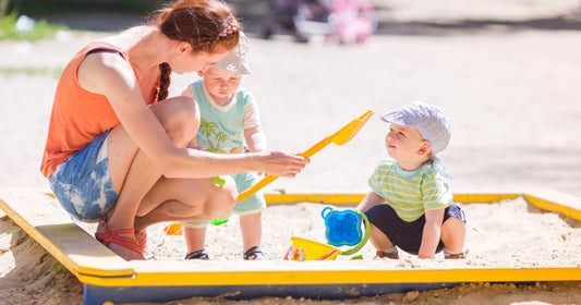 Mom playing with her baby and toddler on the beach during a sunny summer day filled with family fun.