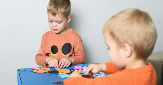 Toddler boys having fun making DIY Halloween crafts and enjoying creative fall activities together