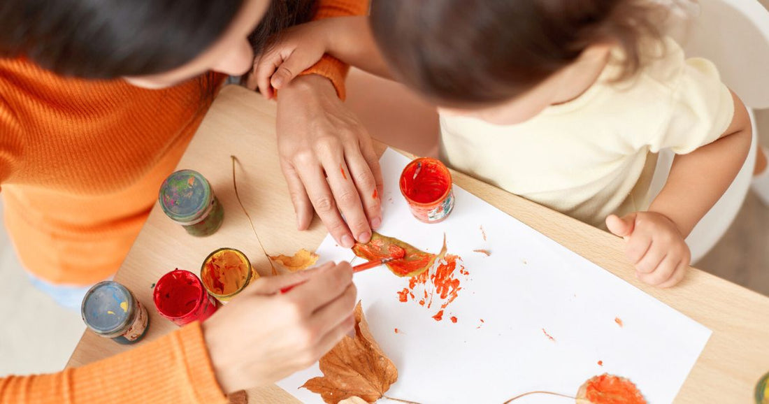 Mom and baby doing a fall-themed sensory arts and crafts activity together, exploring textures and colors perfect for the autumn season.