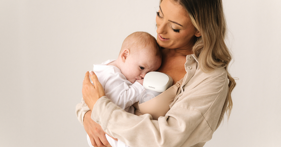 Mother holding baby while using KeaBabies Pulse Breast Pump.