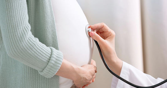 OB-GYN using stethoscope to monitor baby during prenatal checkup – pregnancy health care.