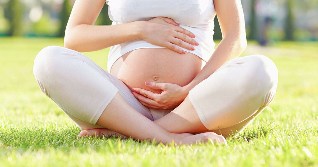 Pregnant woman sitting on grass enjoying a sunny summer day.