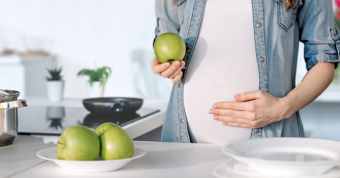 Pregnant woman holding a fresh apple for healthy pregnancy diet.