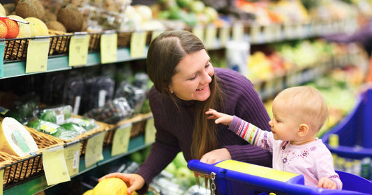 A mom and her baby shopping for healthy produce to create a well-balanced meal.